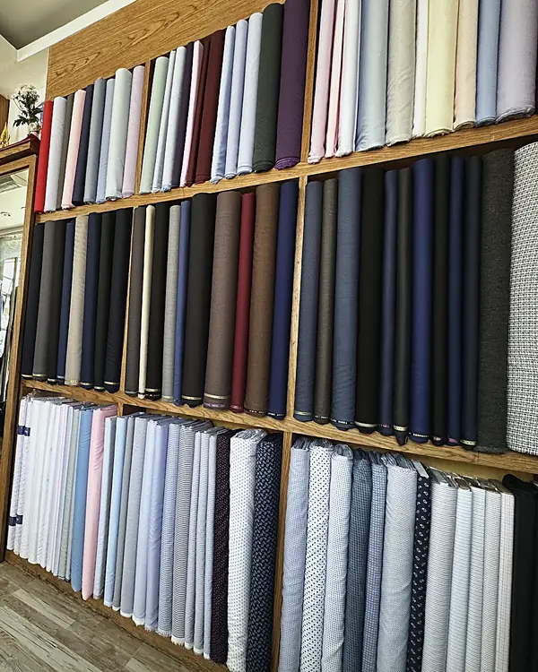 Shelves of suiting and shirting cloth, floor to ceiling, in the Unique Custom Tailor shop in Fisherman's Village