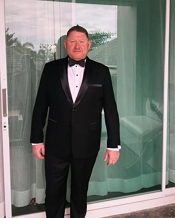 A client in a black tuxedo with satin lapels at his villa