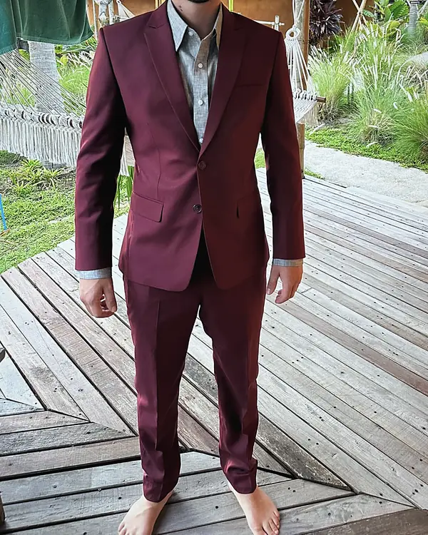 A burgundy suit worn on a wooden deck in a tropical garden