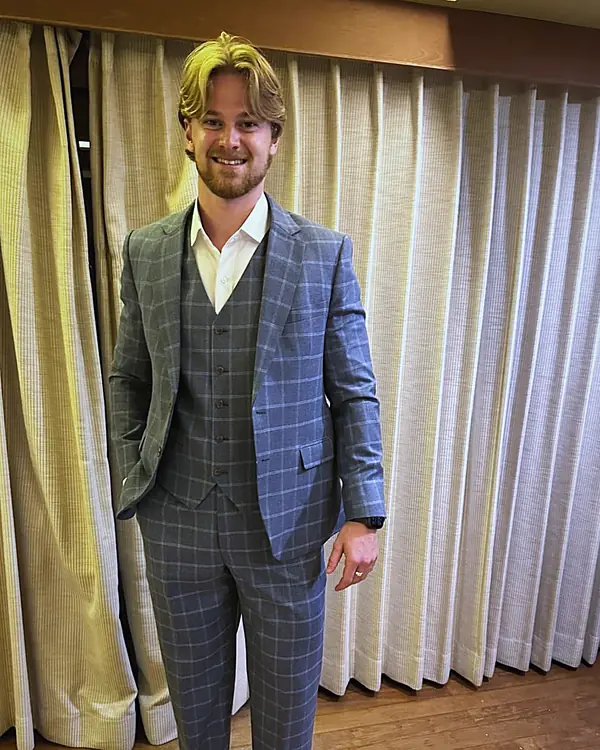 A client in a grey check three-piece suit made by Unique Custom Tailor